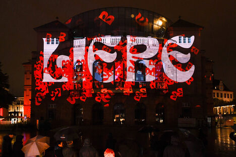 Das Staatstheater beleuchtet mit einem rot-weißen Schriftzug Liebe.