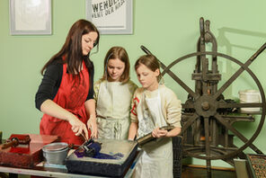 Kinder beim Drucken und Setzen im Druckladen 