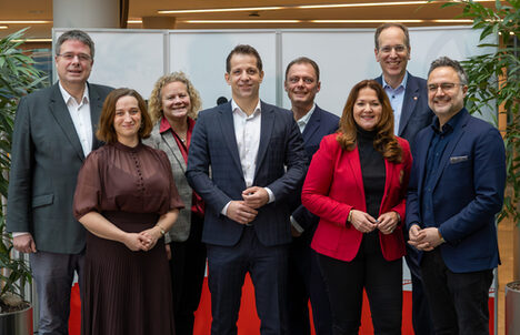 5 Männer und 3 Frauen stehen nebeneinander und lächeln in die Kamera.